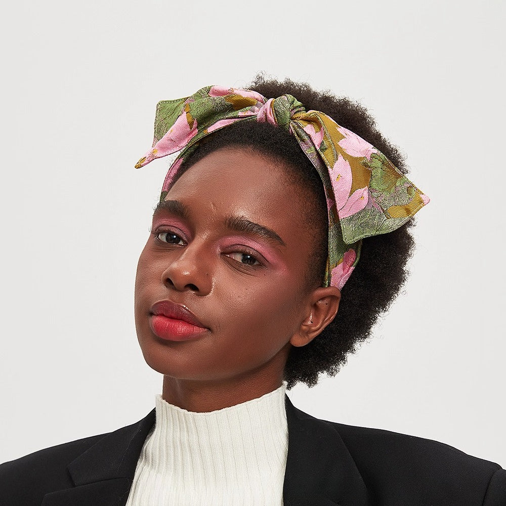 Printed bow headband in pink, green, and mustard floral pattern on woman