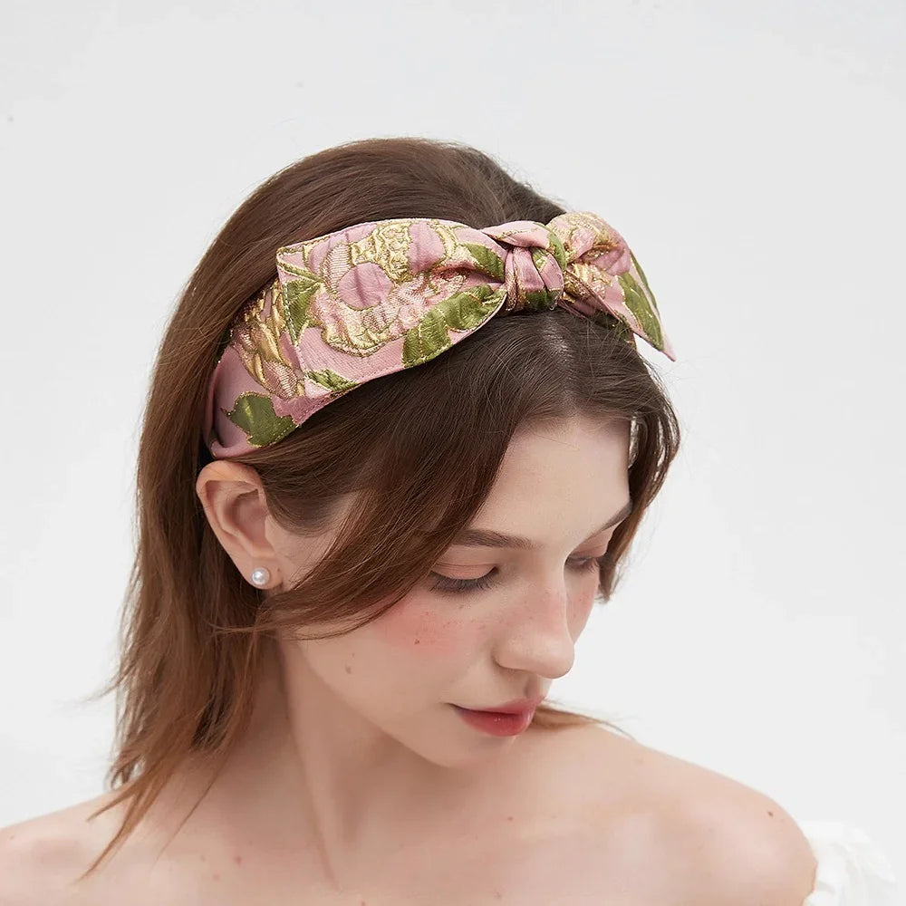 Pink and gold floral bow headband with green leaves, embellished women's accessory
