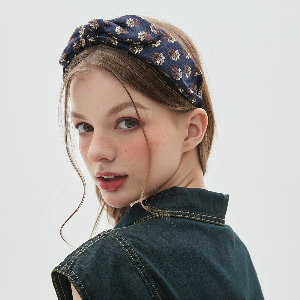 Navy blue printed women's bow headband with small floral pattern in beige and brown