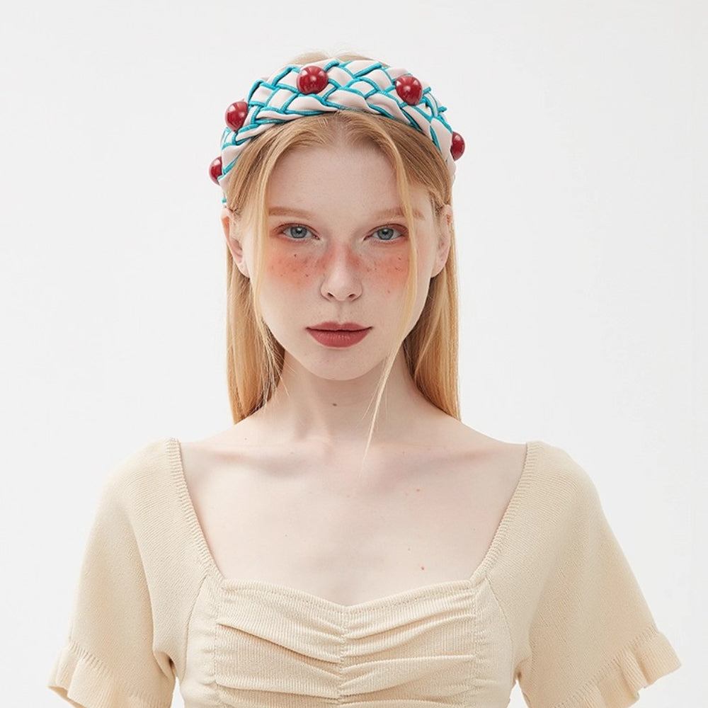Embellished women's headband with white fabric, blue net pattern, and red beads
