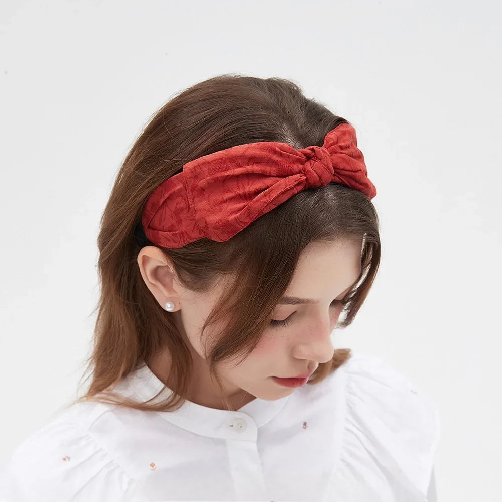 Red bow headband with subtle floral textured fabric, women's bow style accessory