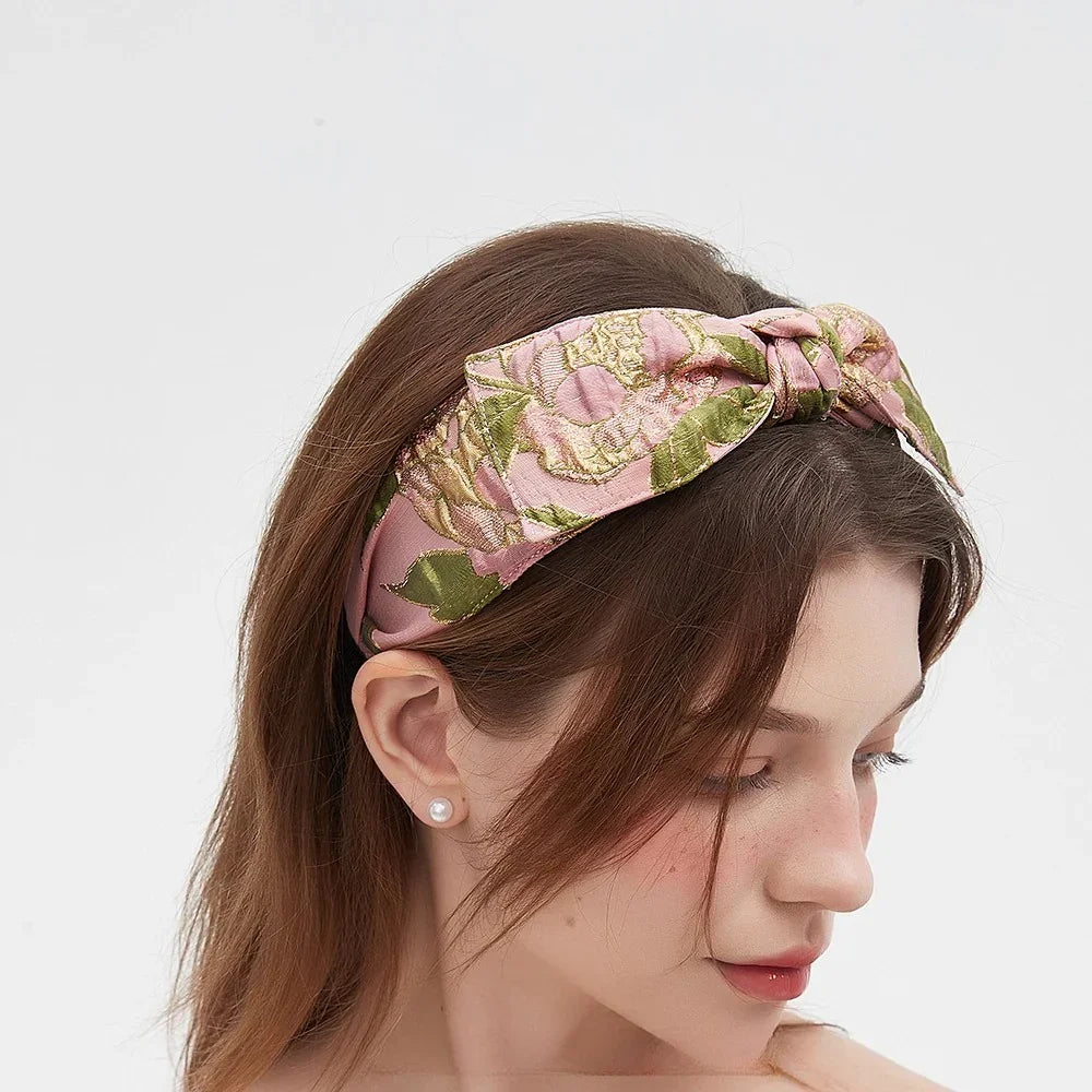 Pink floral printed bow headband with green leaves on woman with brown hair