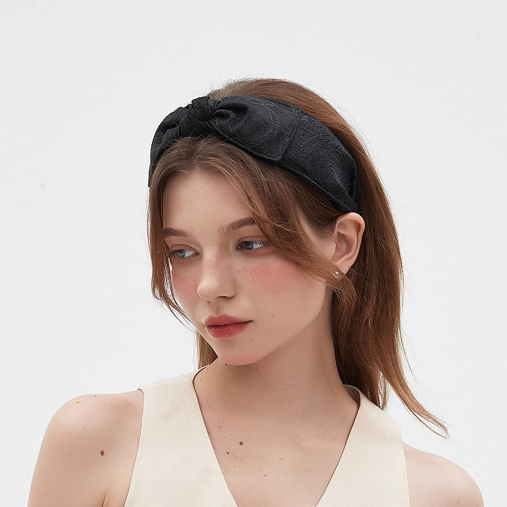 Black embellished women's headband with textured floral pattern and knot detail, stylish accessory