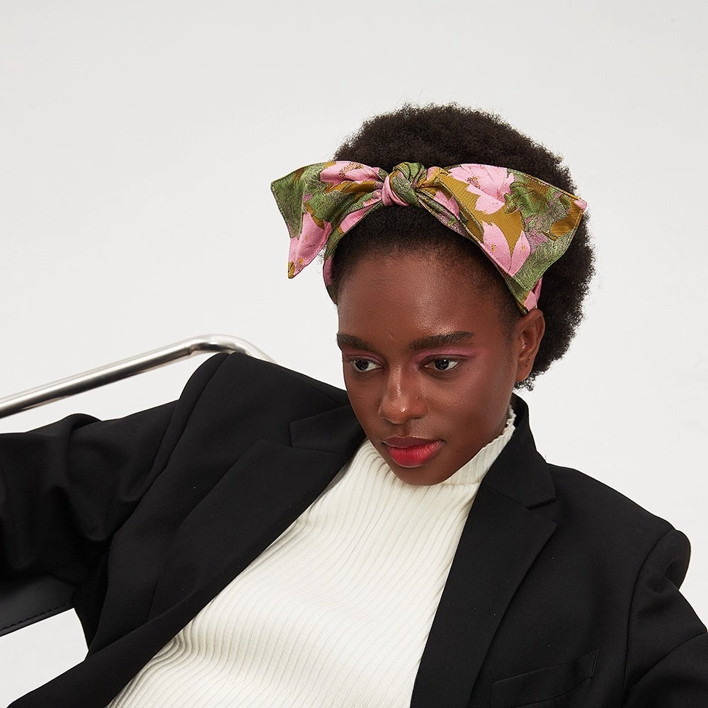 Floral printed bow headband in pink, green, and mustard on model with afro hair