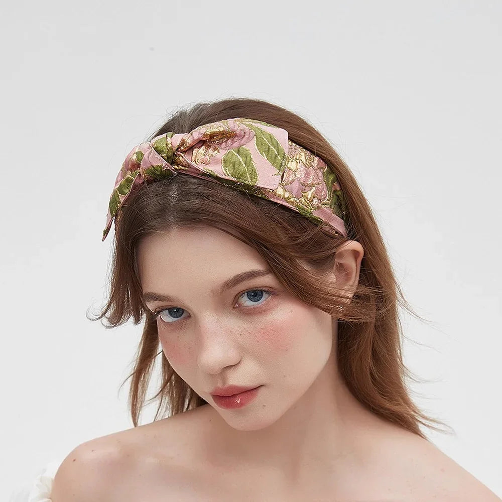 Women's floral printed fabric headband with pink, green, and gold pattern, bow style