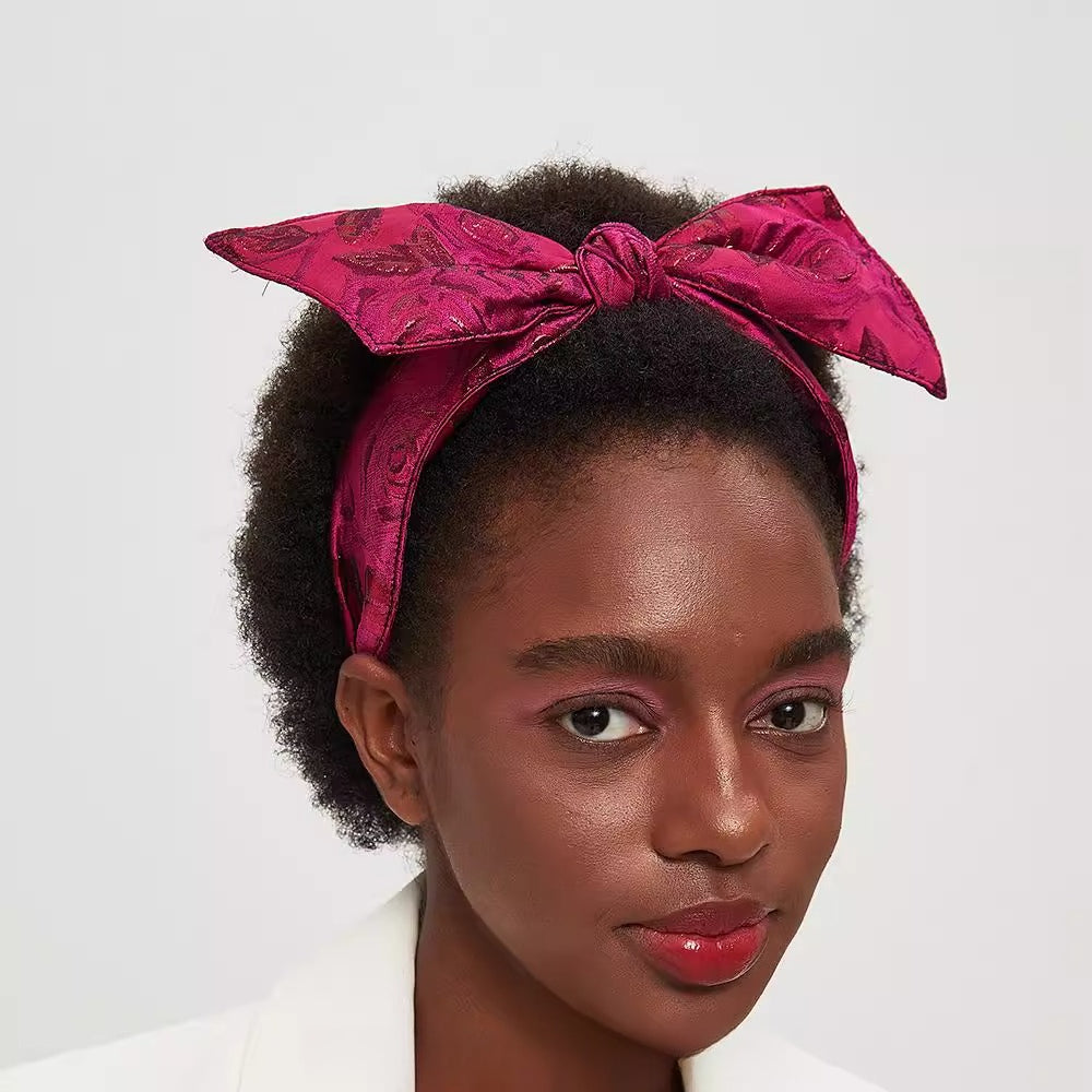 Embellished magenta bow headband with floral jacquard fabric on woman