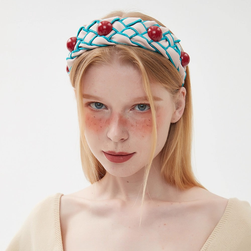 Women's embellished headband with white and turquoise woven fabric and red bead accents