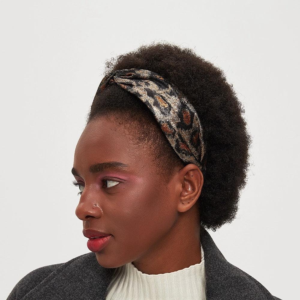 Women's leopard print bow headband in brown and black with metallic accents, stylish accessory