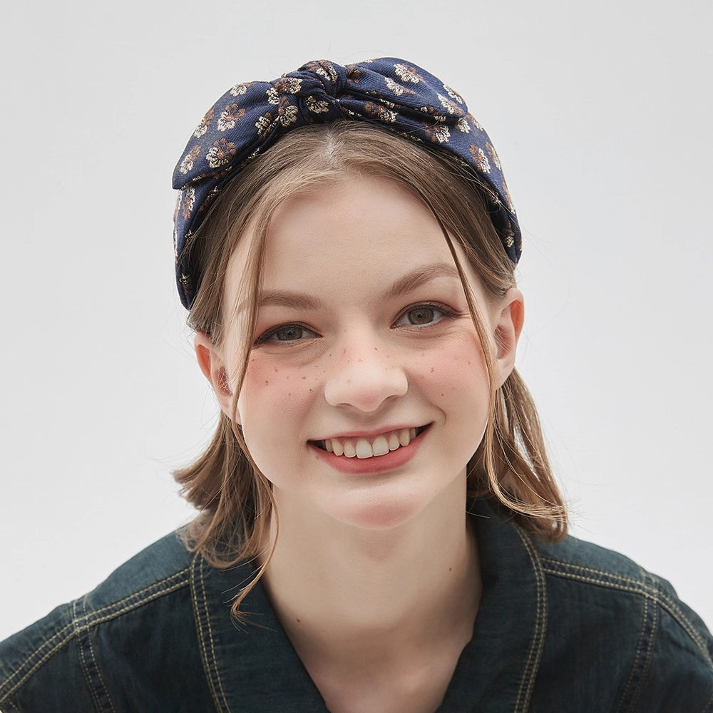 Navy blue floral printed bow headband with textured fabric on woman